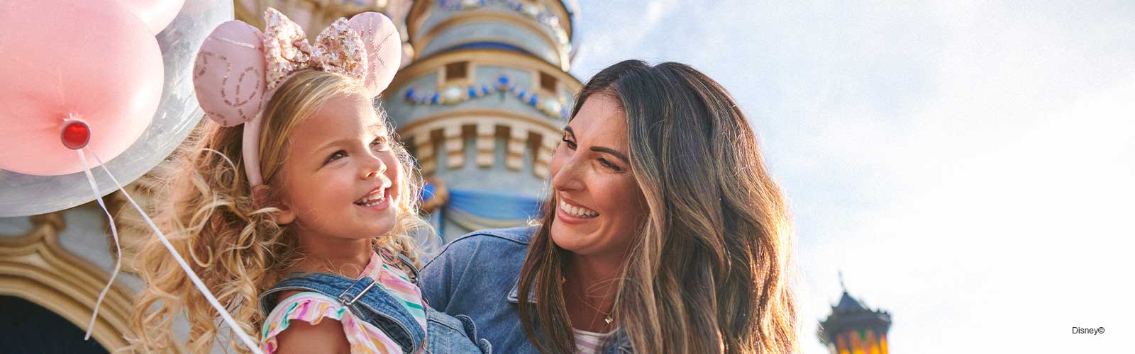 Woman and little girl smiling in front of Cinderella castle