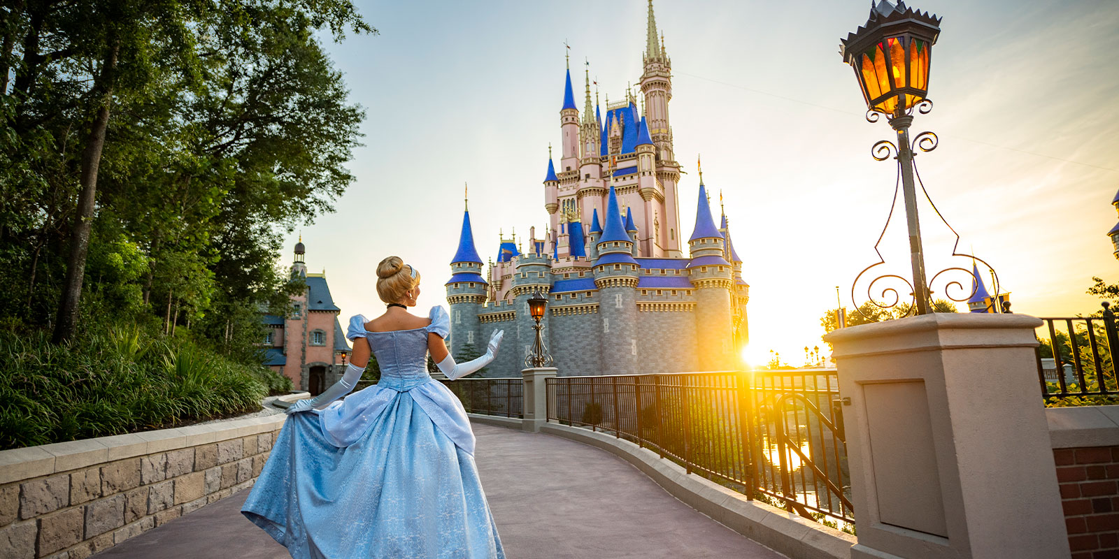 Back photo of Cinderella walking towards the Magic Kingdom castle with the sun set on the background